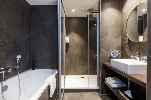 a bathroom with a shower, sink, and tub at The James Rotterdam in Rotterdam
