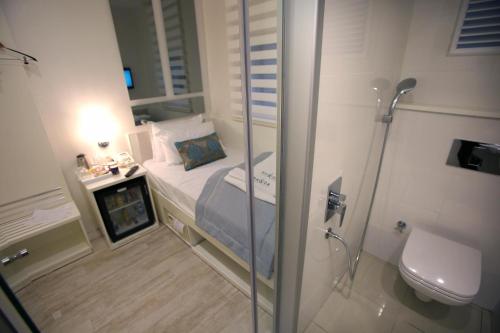 Ravvda Hotel في إسطنبول: حمام صغير مع سرير ودش
