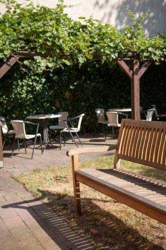 a wooden bench sitting next to a table and chairs at Hotel Adagio in Leipzig