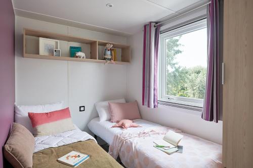 Habitación pequeña con cama y ventana en Mobil Home XXL 4 chambres - Camping Les Tropiques, en Torreilles