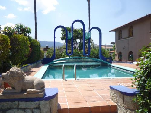 a swimming pool with a lion statue in front of it at Hotel Posada Los Arcos in Oaxaca City