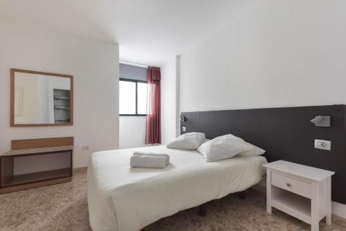 a bedroom with a large white bed with a mirror at Apartamento Pardela in Playa de San Juan