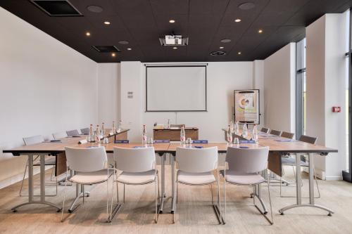 a conference room with a long table and white chairs at Campanile Rennes Sud - Saint Jacques in Saint-Jacques-de-la-Lande