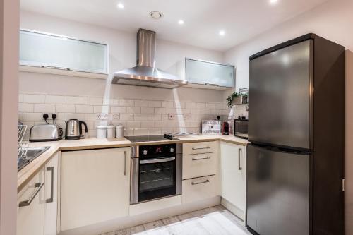 a kitchen with white cabinets and a stainless steel refrigerator at Host & Stay - Baltic Balcony Apt in Liverpool