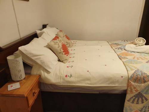 uma pequena cama com lençóis brancos e almofadas em The craw inn em Eyemouth