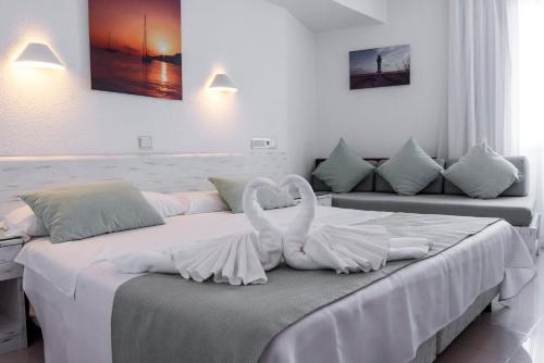 due cigni bianchi seduti su un letto in una stanza di Hostal Bellavista Formentera a La Savina