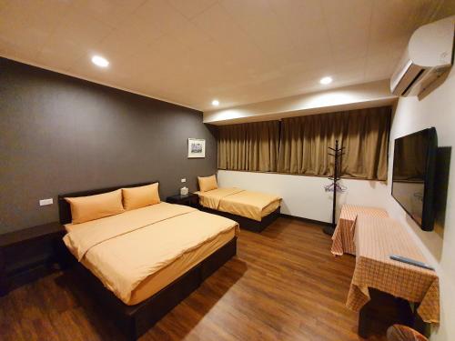 een slaapkamer met 2 bedden en een flatscreen-tv bij Fun Shili B&B in Shuili