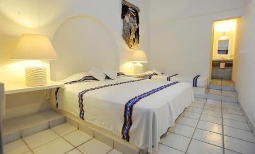 a white bedroom with a bed and two lamps at Reconocido por su ubicacion calidez y hospitalidad in Ixtapa