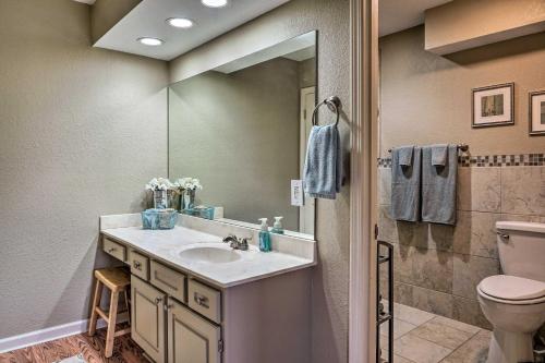 La salle de bains est pourvue d'un lavabo, de toilettes et d'un miroir. dans l'établissement Condo Amidst Branson Action with Pool Access and Golf!, à Branson