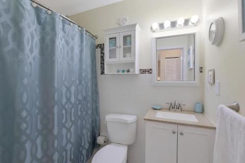 a bathroom with a shower curtain and a toilet and a sink at Peaceful condo with pool and brief walk to beach in Marco Island