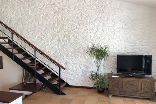 a living room with a tv and a staircase at ROQUES - Casa en primera línea de mar en CADAQUÉS in Cadaqués