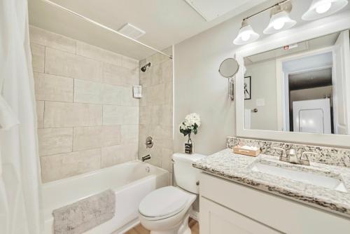 La salle de bains blanche est pourvue d'une baignoire, de toilettes et d'un lavabo. dans l'établissement The Dallas Vibe and Free Arboretum Tickets, à Dallas