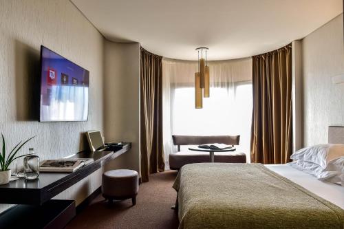 a hotel room with a bed and a desk at Porto Palácio Hotel by The Editory in Porto
