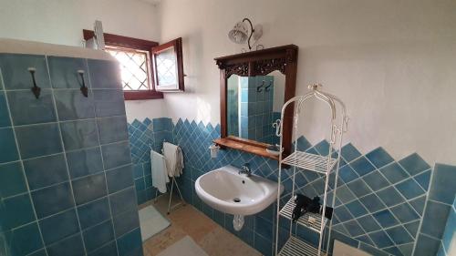 a blue tiled bathroom with a sink and a mirror at B&B La Murichessa in Arzachena