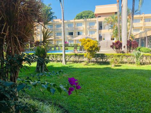 a building with a yard with purple flowers in the grass at Hotel Villa Florida Córdoba in Córdoba