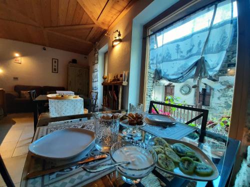 a table with plates of food on it with a window at CasAlpAca B&B con sauna a Prali in Prali