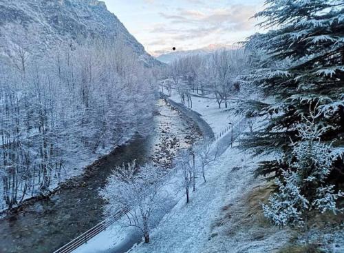 a snow covered valley with a river and trees at Duplex a la plaça Major in El Pont de Suert