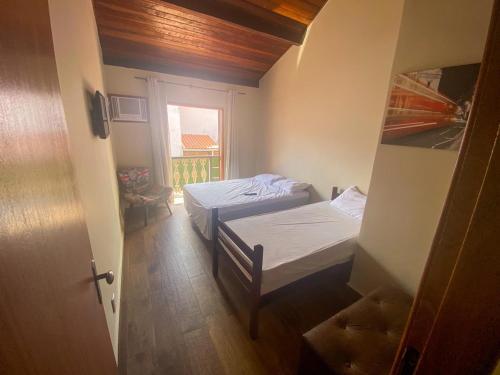 a small room with two beds and a window at RESIDENCIA DOS LEAIS in Arraial do Cabo