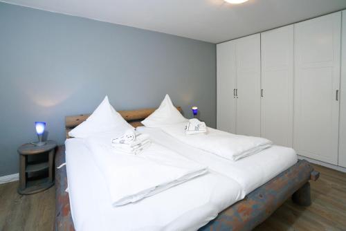 um quarto com 2 camas e lençóis brancos em Haus-Carola-App-11-Sylter-Seestern em Wenningstedt