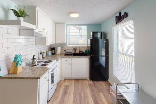 a kitchen with a black refrigerator and white cabinets at The Comfi Coral - 2 Bed Apartment Home Studio B in Baytown