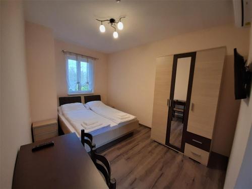 1 dormitorio con cama, mesa y espejo en Bársony Vendéglő és Panzió, en Szécsény