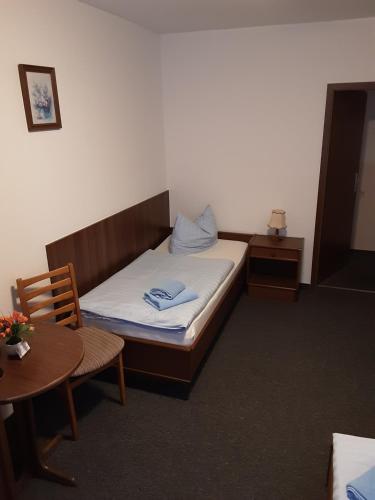 Kleines Zimmer mit einem Bett und einem Tisch in der Unterkunft Goldener Anker in Genthin