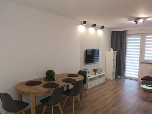 uma sala de estar com uma mesa e cadeiras e uma televisão em Apartament Marcella em Gorzów Wielkopolski