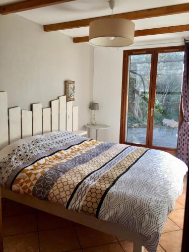 une chambre avec un grand lit avec une grande fenêtre dans l'établissement Gite des oliviers, à La Roque-sur-Cèze