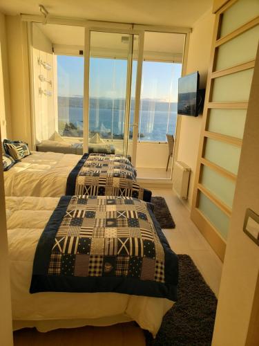 two beds in a room with a view of the ocean at Departamento full vista al Mar ReñacaConcon in Viña del Mar