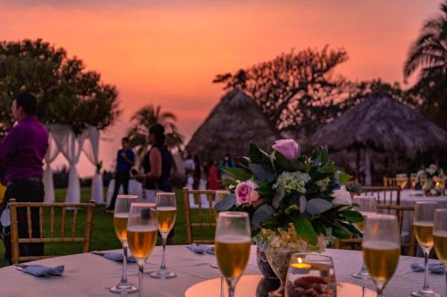 una mesa con copas de vino y un jarrón de flores en Atami Escape Resort, en La Libertad