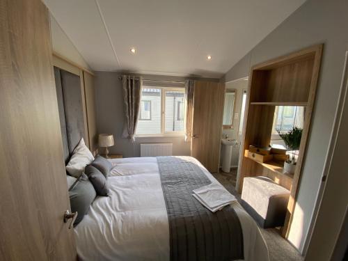 a bedroom with a bed and a window at Brand new Sea view beach lodge Trecco bay 3 bedroom in Porthcawl