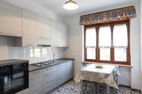 a kitchen with white cabinets and a window and a table at Les 2 Soeurs in Pont-Saint-Martin