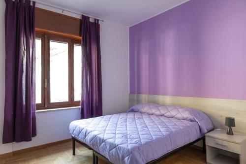 um quarto roxo com uma cama e uma janela em Les 2 Soeurs em Pont-Saint-Martin