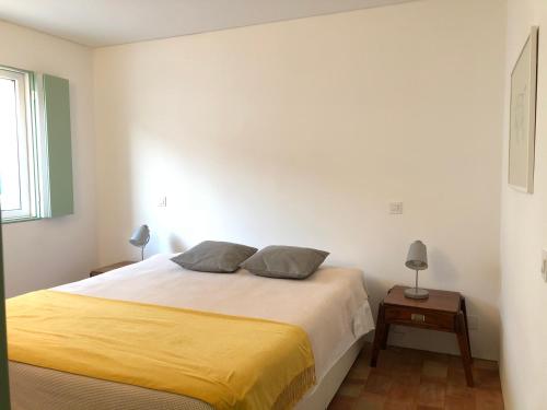 a bedroom with a large bed with a yellow blanket at Casa do Côvo - Suite in Porto Covo