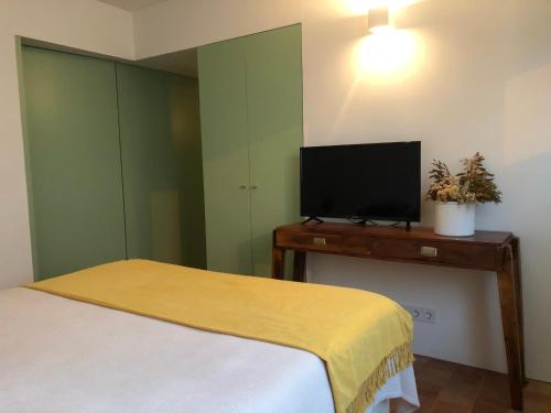 a bedroom with a bed and a flat screen tv at Casa do Côvo - Suite in Porto Covo