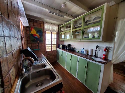 a kitchen with green cabinets and a sink at Prins Hendrik Suites in Paramaribo