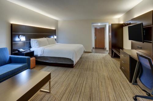 a hotel room with a bed and a couch and a tv at Holiday Inn Express & Suites Troy by IHG in Troy