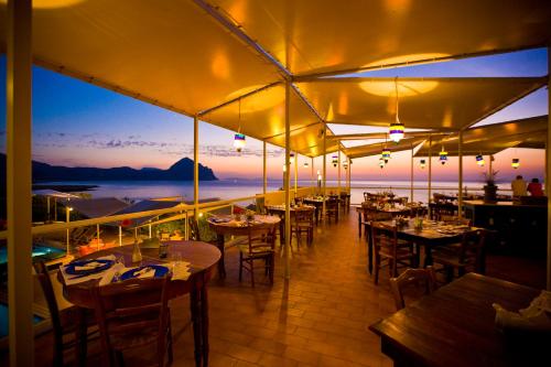 a restaurant with tables and chairs with a view of the ocean at Hotel Pocho in San Vito lo Capo
