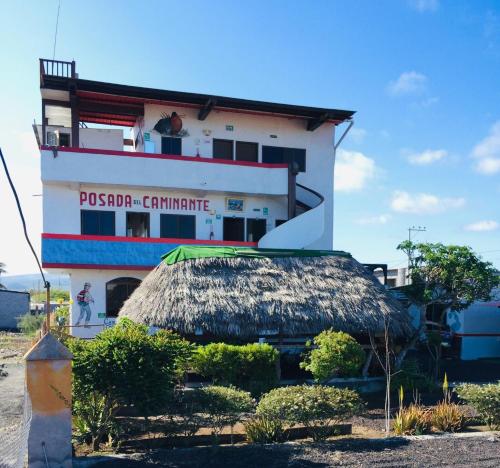 a building with a thatch roof in front of it at Posada del Caminante in Puerto Villamil