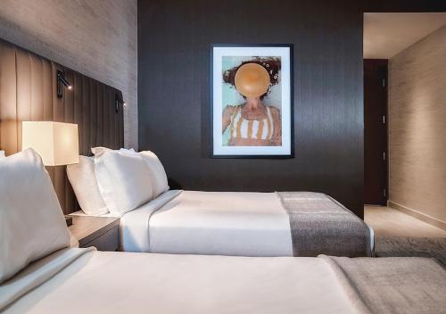 a hotel room with two beds and a painting on the wall at THesis Hotel Miami Coral Gables, Curio Collection by Hilton in Miami