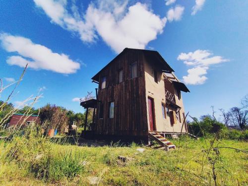 une vieille maison assise dans un champ herbeux dans l'établissement Raices del Mar, à La Pedrera