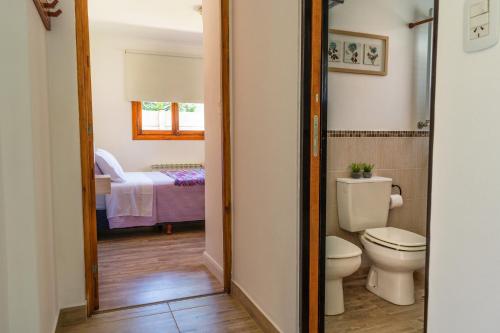 a bathroom with a toilet and a bed at Aires De Montaña in El Bolsón