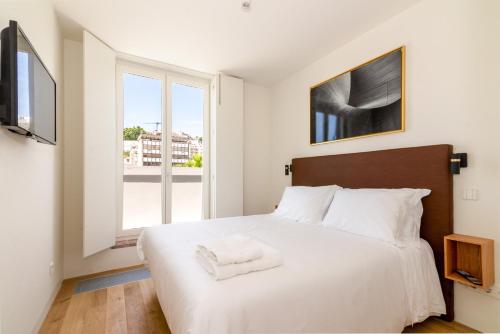 1 dormitorio con 1 cama blanca grande y ventana en Liberdade 12 by The Good Neighbour in Lisbon en Lisboa