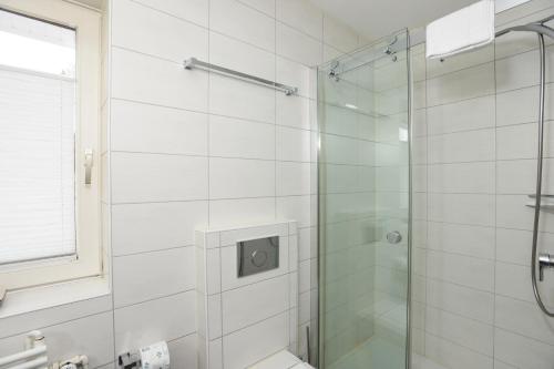 une salle de bain avec une douche avec une porte vitrée dans l'établissement Fesker-4, à Morsum