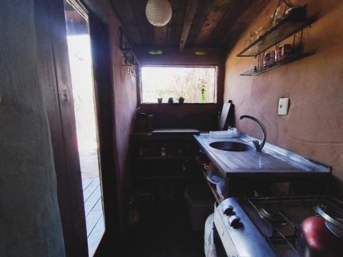 uma pequena cozinha com um lavatório e uma janela em Raices del Mar em La Pedrera