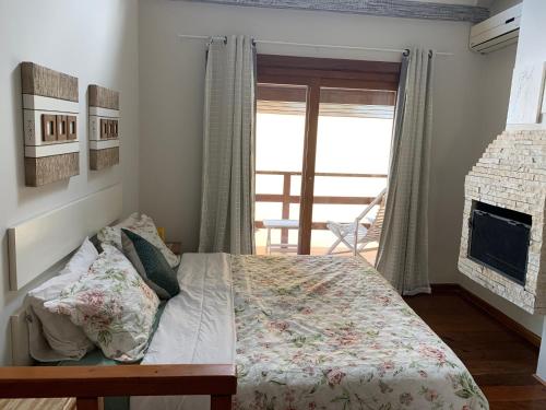 a bedroom with a bed and a fireplace and a window at Chalé aconchegante para família no Centro in Penedo