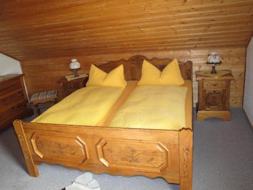 a bedroom with a wooden bed with yellow sheets and pillows at Ferienhaus-Haidweg-Wohnung-5 in Haidmühle