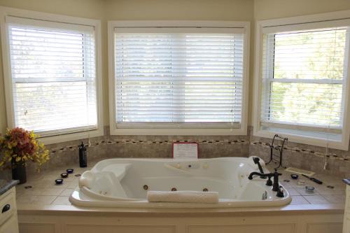 a white bath tub in a bathroom with three windows at Norfolk Guest House Inn in Guelph
