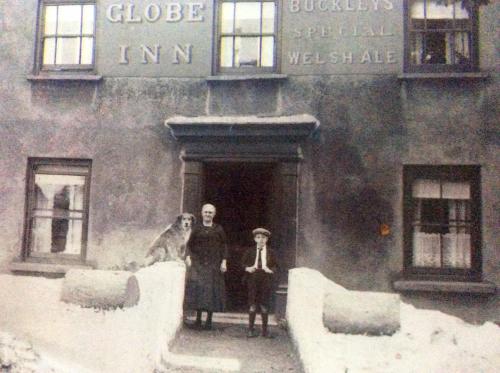 an old photo of two people and a dog in front of a building at Globe Guesthouse in Burry Port