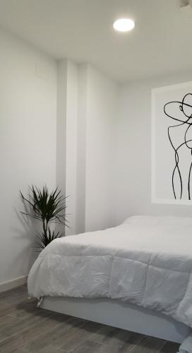 a white bedroom with a bed and a plant at Suite by Hawkins Exterior 2B in Algeciras